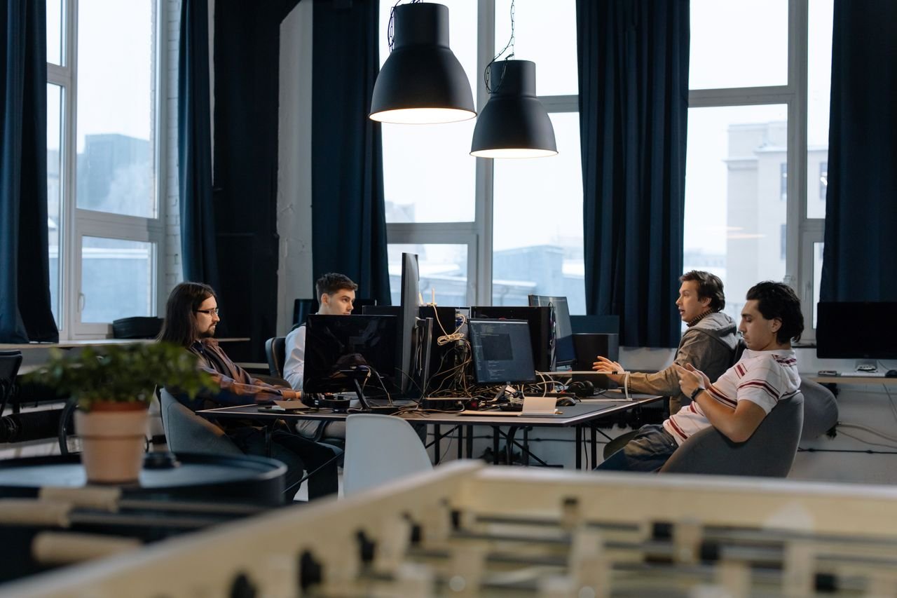 Home Workers collaborate in a modern office with computers, showcasing teamwork in technology development.