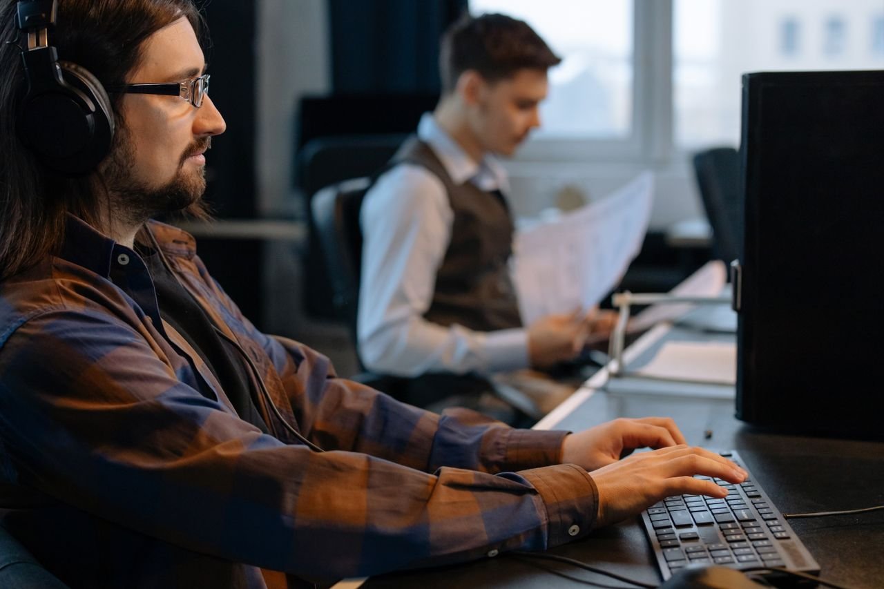 Home Two office workers focused on tasks at their desks in a modern workspace.